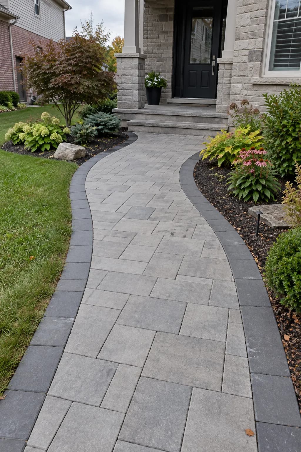 Curved grey paver walkway with a dark border leading to the front porch