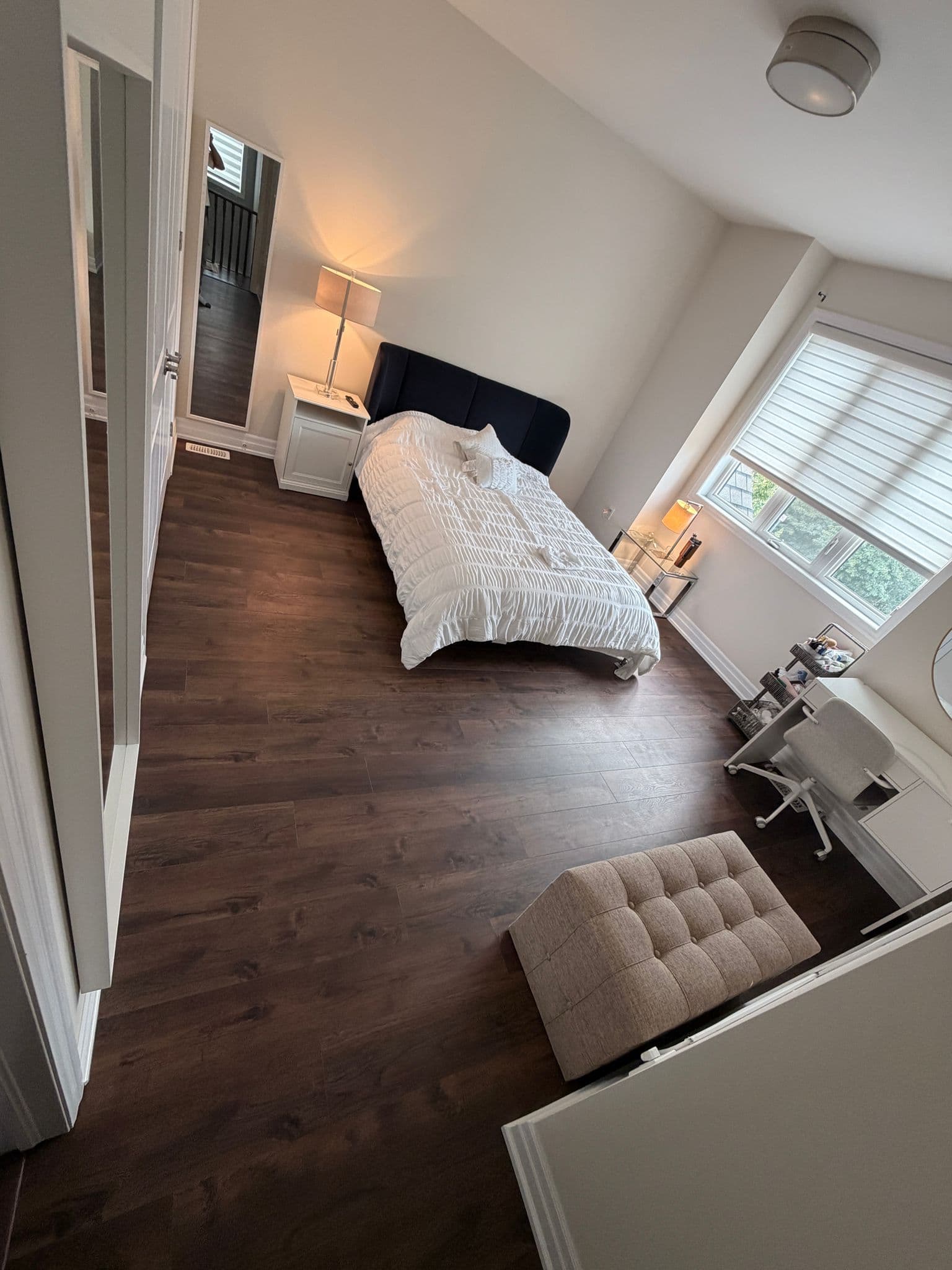 New dark plank flooring across a bedroom with a bay window