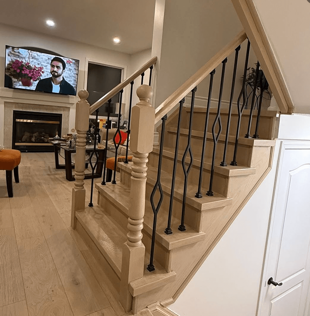 Light oak flooring in an open living room beside a staircase with iron spindles