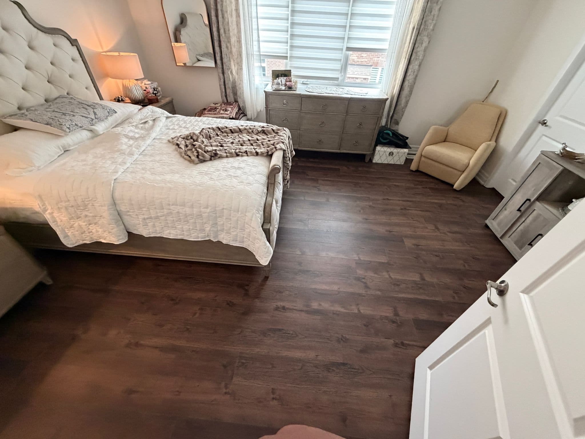 Dark wood-look flooring installed through a primary bedroom